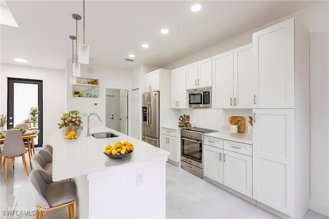 kitchen with sink, appliances with stainless steel finishes, white cabinetry, a kitchen breakfast bar, and decorative light fixtures