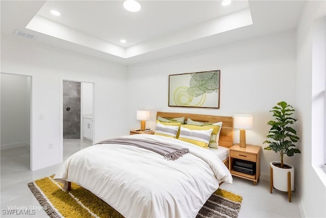 bedroom featuring connected bathroom and a raised ceiling