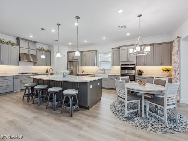 kitchen featuring stainless steel appliances, a large island, sink, and hanging light fixtures