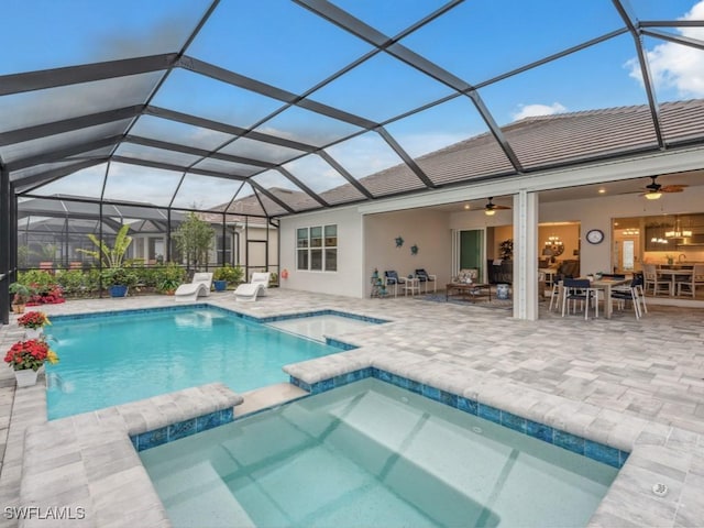 view of pool with an in ground hot tub, ceiling fan, and glass enclosure