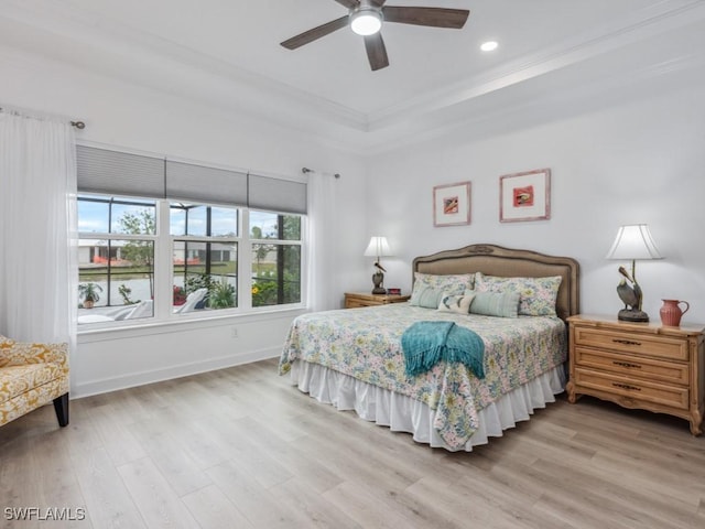 bedroom with a tray ceiling, crown molding, light hardwood / wood-style floors, and ceiling fan