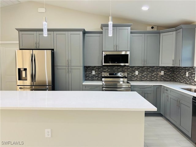 kitchen with appliances with stainless steel finishes, vaulted ceiling, and decorative backsplash