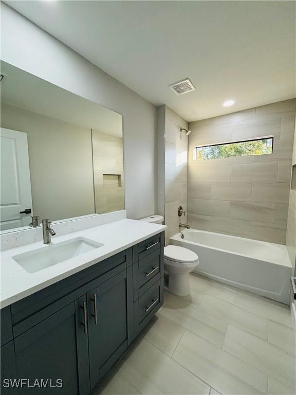 full bathroom featuring toilet, tiled shower / bath, and vanity