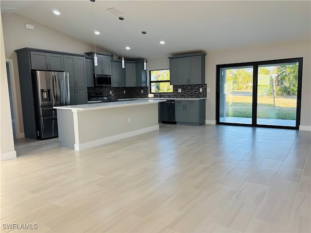 kitchen with lofted ceiling, stainless steel appliances, hanging light fixtures, and a kitchen island