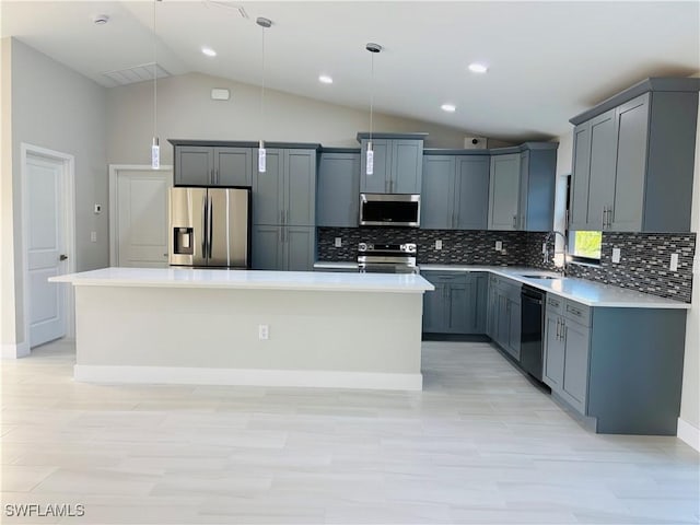 kitchen featuring sink, vaulted ceiling, a kitchen island, pendant lighting, and appliances with stainless steel finishes