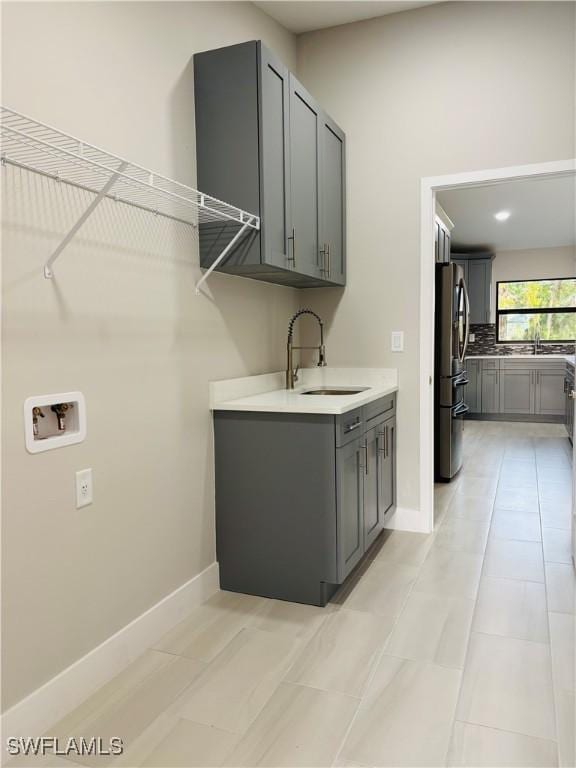 laundry room featuring sink, light tile patterned flooring, hookup for a washing machine, and cabinets