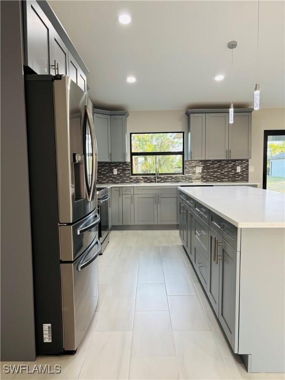 kitchen with decorative light fixtures, backsplash, gray cabinetry, and appliances with stainless steel finishes