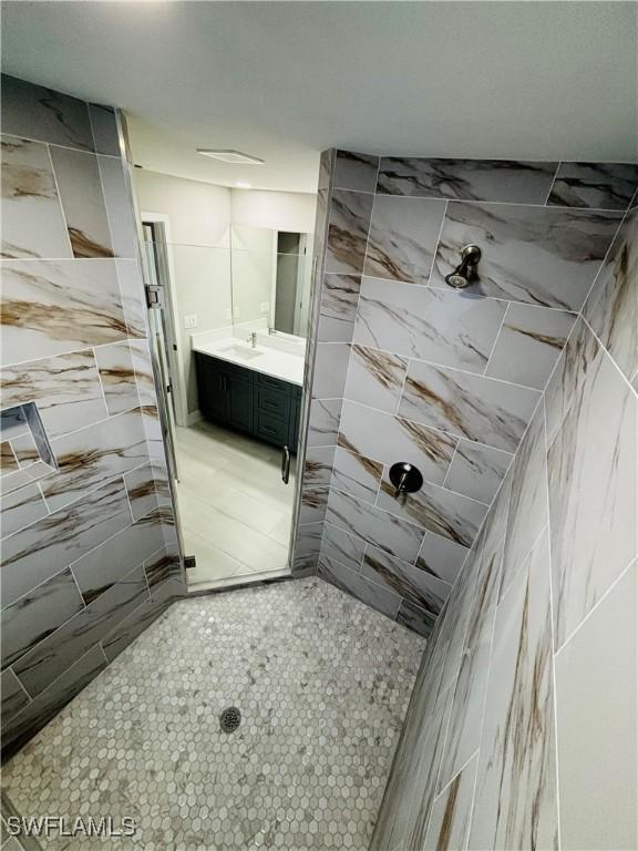 bathroom with a tile shower and vanity