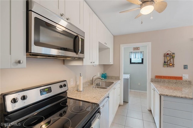 kitchen featuring white cabinetry, stainless steel appliances, light tile patterned flooring, light stone countertops, and sink