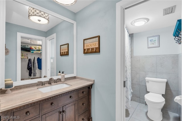 bathroom featuring toilet, vanity, tile walls, and tile patterned floors