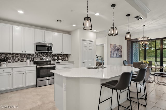 kitchen featuring a kitchen island with sink, sink, stainless steel appliances, and white cabinetry