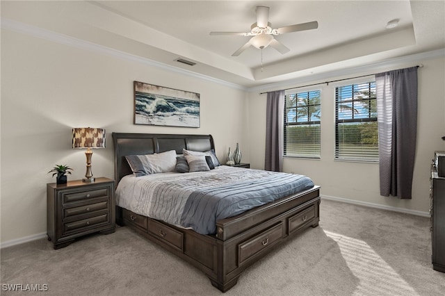 carpeted bedroom featuring ceiling fan, a tray ceiling, and ornamental molding