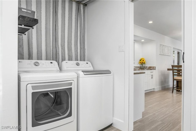 clothes washing area featuring washing machine and clothes dryer and light wood-type flooring