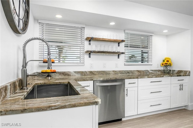 kitchen featuring sink, dishwasher, dark stone countertops, light hardwood / wood-style floors, and white cabinets