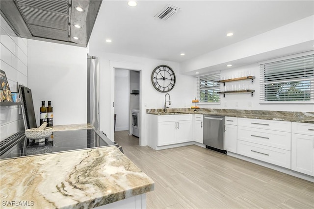 kitchen with sink, stainless steel dishwasher, washer / clothes dryer, light stone countertops, and white cabinets