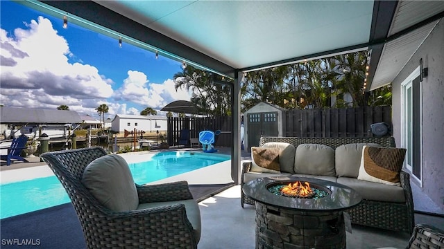 view of swimming pool featuring a patio, an outdoor living space with a fire pit, and a storage shed