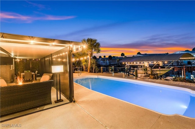 pool at dusk with a fire pit and a patio area