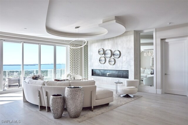 living room featuring a tray ceiling and a water view