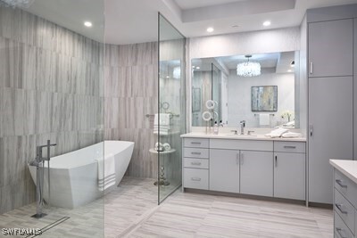 bathroom with vanity, shower with separate bathtub, and tile walls