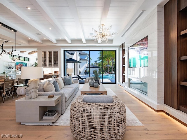 living room with light wood-type flooring, a fireplace, beamed ceiling, and a chandelier