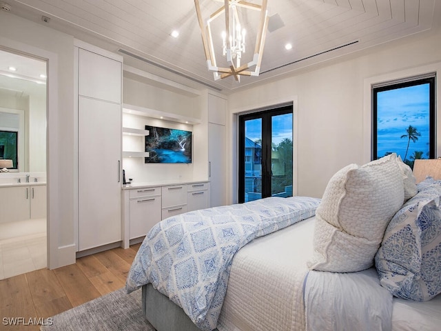 bedroom featuring ensuite bathroom, light wood-type flooring, access to exterior, a chandelier, and sink