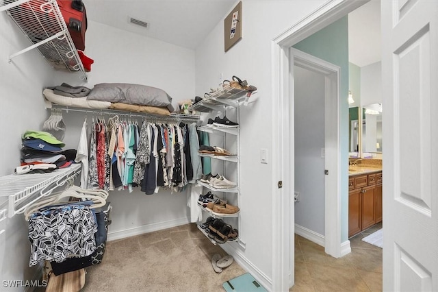 walk in closet with sink and light colored carpet