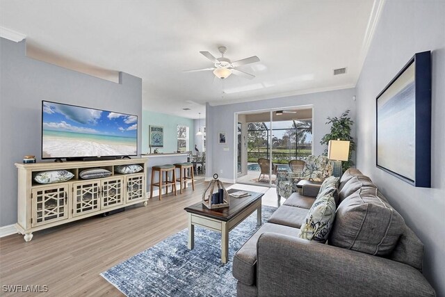 living room featuring crown molding, ceiling fan, and light hardwood / wood-style flooring