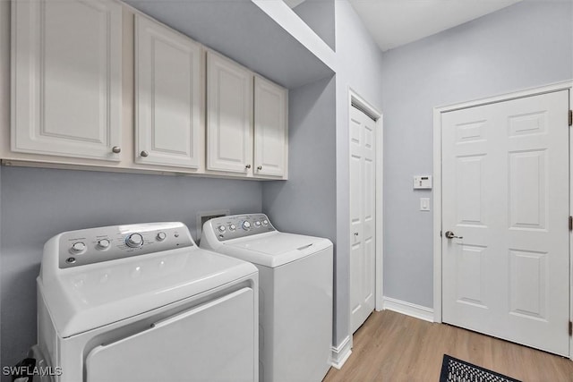 washroom with cabinets, separate washer and dryer, and light wood-type flooring