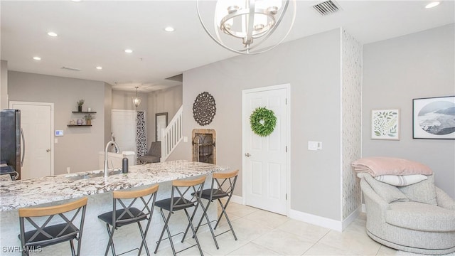 kitchen featuring decorative light fixtures, light stone counters, light tile patterned floors, stainless steel refrigerator, and a chandelier