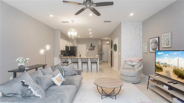 tiled living room featuring ceiling fan with notable chandelier