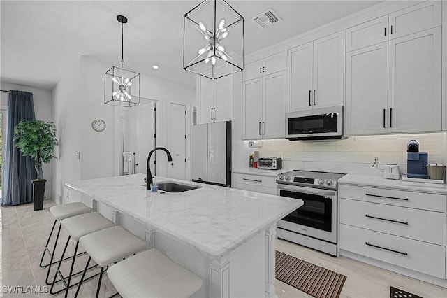 kitchen with white cabinets, sink, an island with sink, and white appliances