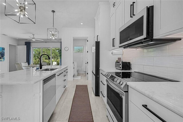 kitchen with white cabinets, appliances with stainless steel finishes, a center island with sink, and sink