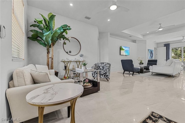 living room featuring a raised ceiling and ceiling fan