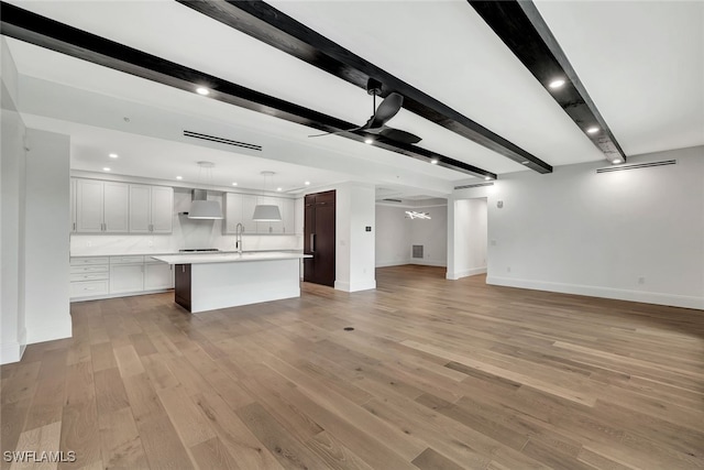 unfurnished living room with beam ceiling, light hardwood / wood-style floors, and ceiling fan