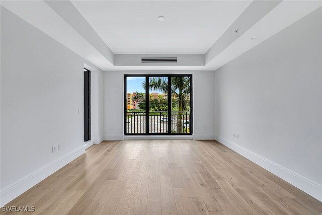 empty room featuring light hardwood / wood-style floors and a tray ceiling