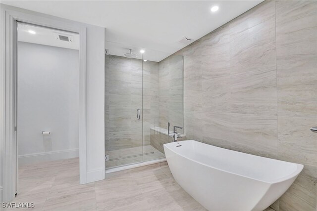 bathroom featuring tile walls and independent shower and bath