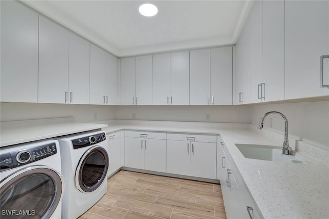 clothes washing area featuring cabinets, sink, and washing machine and dryer