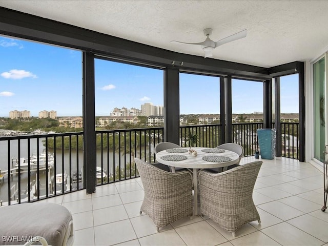 sunroom featuring ceiling fan and a water view