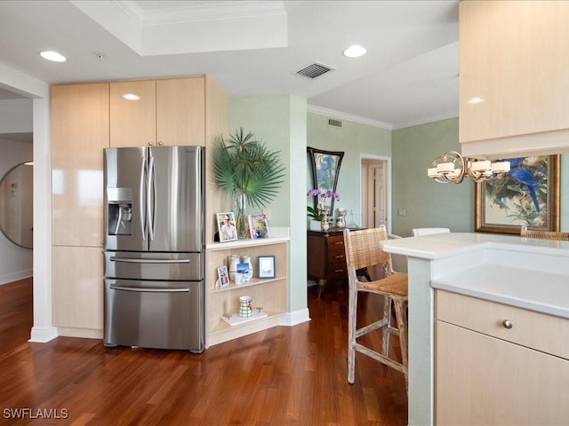 kitchen with light brown cabinets, stainless steel fridge, a breakfast bar, crown molding, and dark wood-type flooring