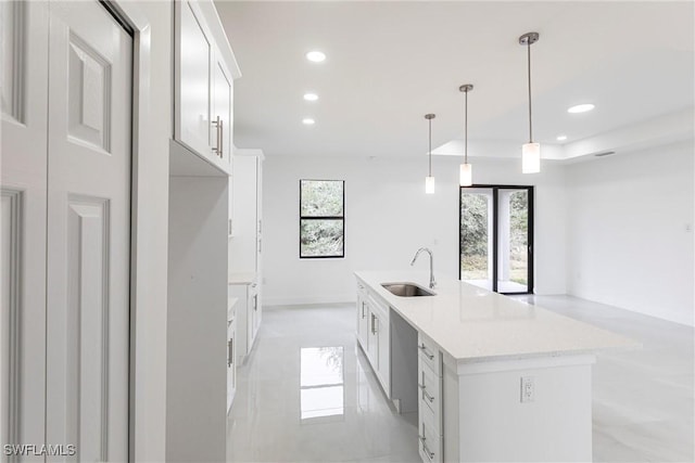 kitchen featuring white cabinetry, sink, an island with sink, and decorative light fixtures