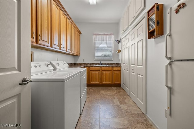 clothes washing area with washer and dryer, sink, and cabinets