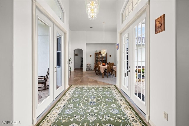 doorway with french doors, a notable chandelier, and tile patterned floors