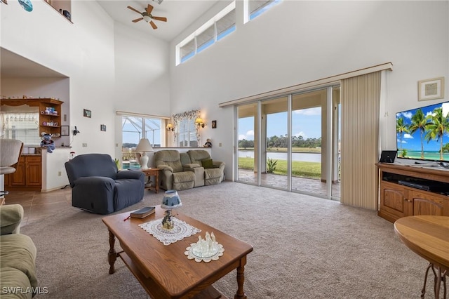 carpeted living room featuring ceiling fan, plenty of natural light, and a high ceiling