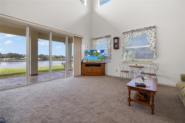 interior space featuring a high ceiling, a water view, and carpet flooring