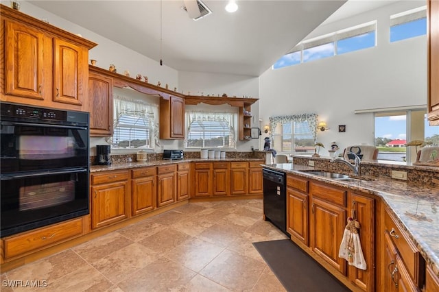 kitchen featuring a high ceiling, sink, black appliances, and dark stone countertops