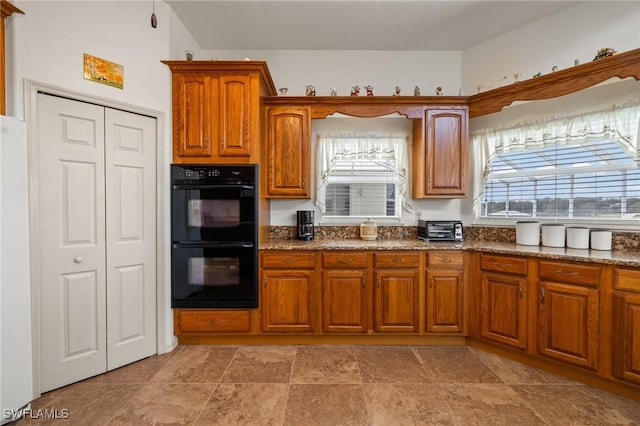 kitchen featuring black double oven and dark stone counters