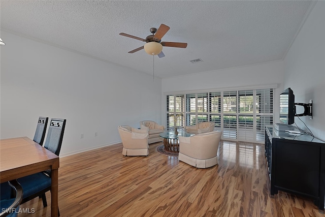 sitting room featuring ceiling fan, wood-type flooring, and a textured ceiling