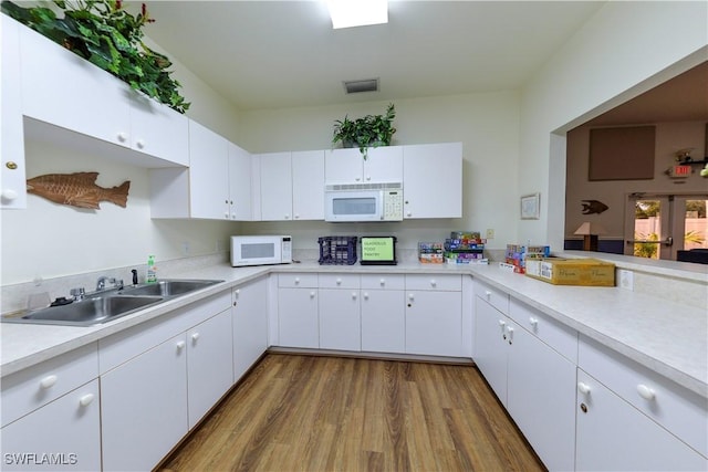 kitchen with wood-type flooring, sink, and white cabinetry