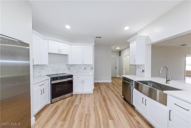 kitchen with decorative backsplash, white cabinets, appliances with stainless steel finishes, and sink