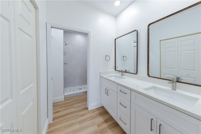 bathroom featuring hardwood / wood-style floors, vanity, and a tile shower